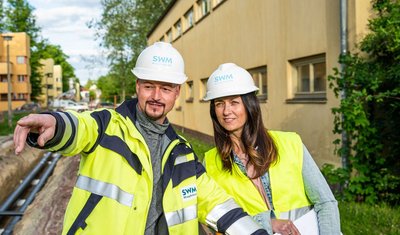 Bau Fernwärmeleitung in der Beimssiedlung Zwei SWM Mitarbeiter besprechen den Bau der Fernwärmeleitung in der Beimssiedlung