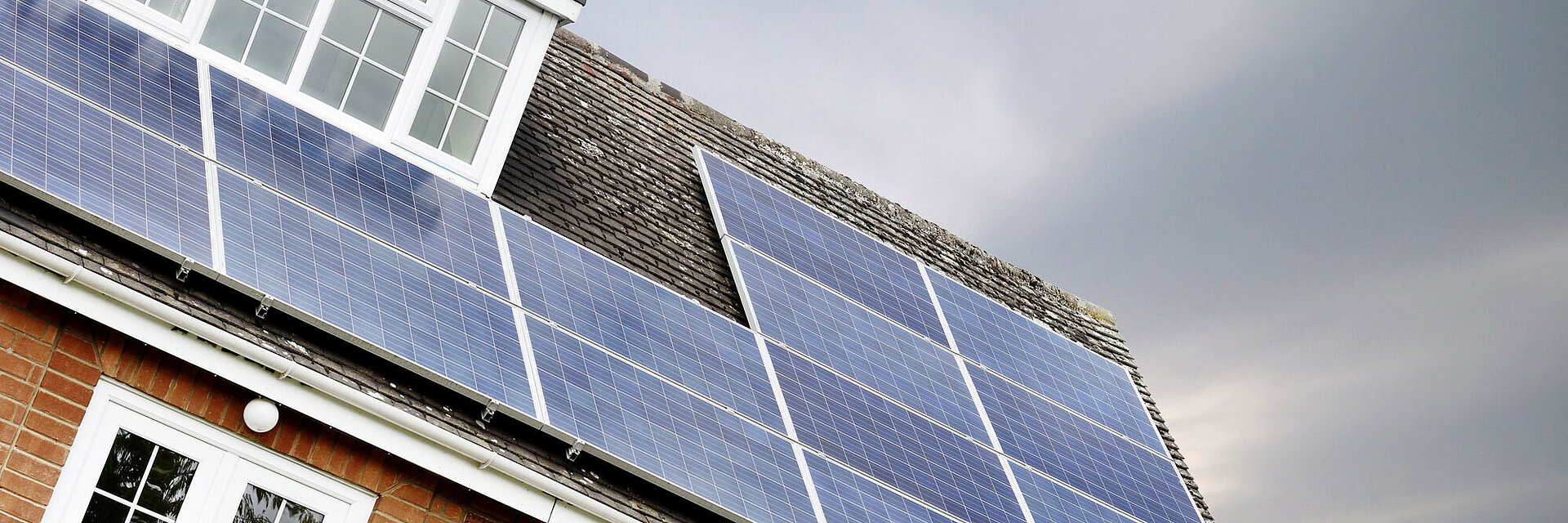 PV Anlange auf einem Haus mit dunklem Himmel im Hintergrund