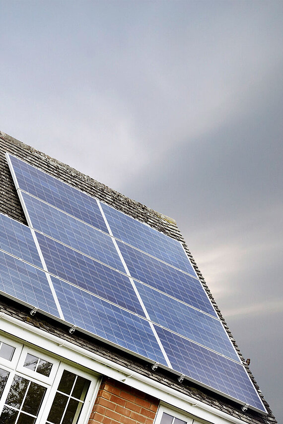 PV Anlange auf einem Haus mit dunklem Himmel im Hintergrund