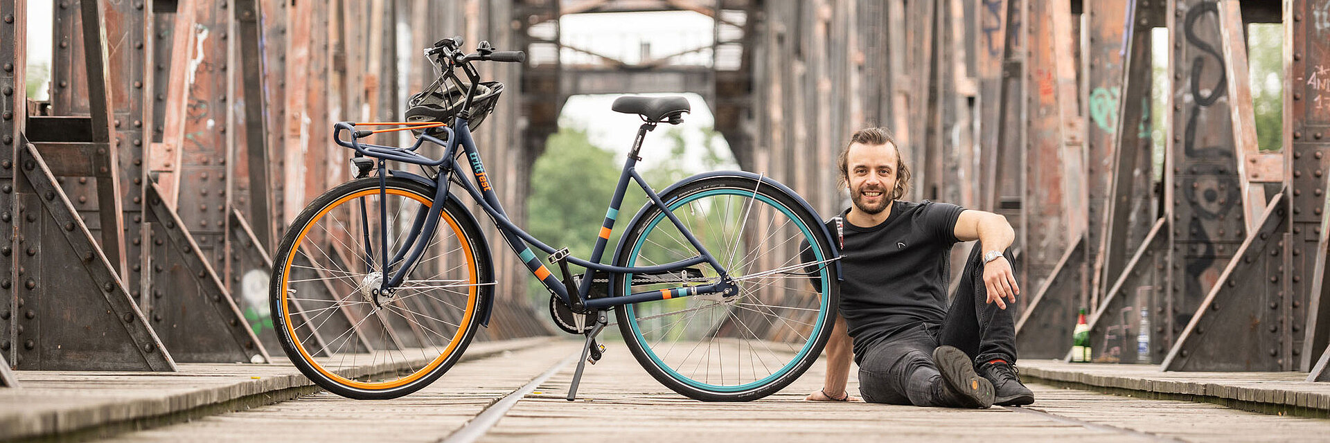 junger Mann sitzt neben trittfest Rad mike auf der Hubbrücke