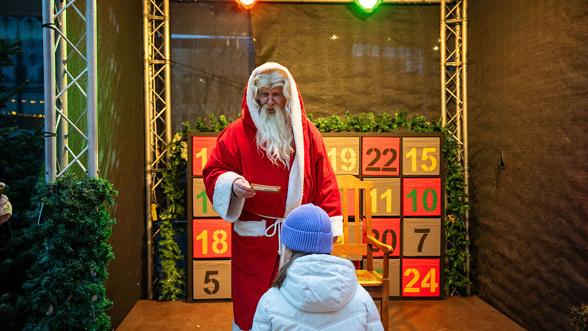 Weihnachtsmann übergibt Geschenk an ein Kind