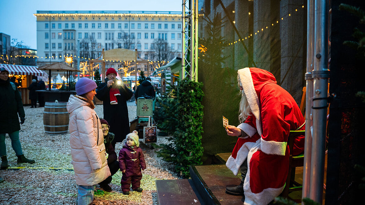 Kinder stehen vor der Bühne, auf der der Weihnachtsmann sitzt