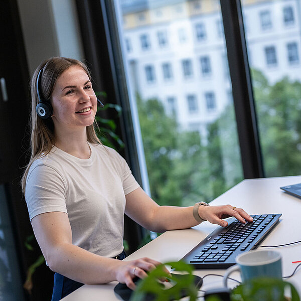 kaufmännische Auszubildende sitzt am Schreibtisch und arbeitet am Computer