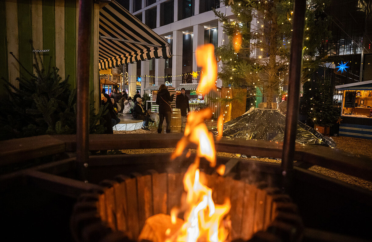 Blick auf den SWM Weihnachtsmarkt mit Feuertonne im Vordergrund