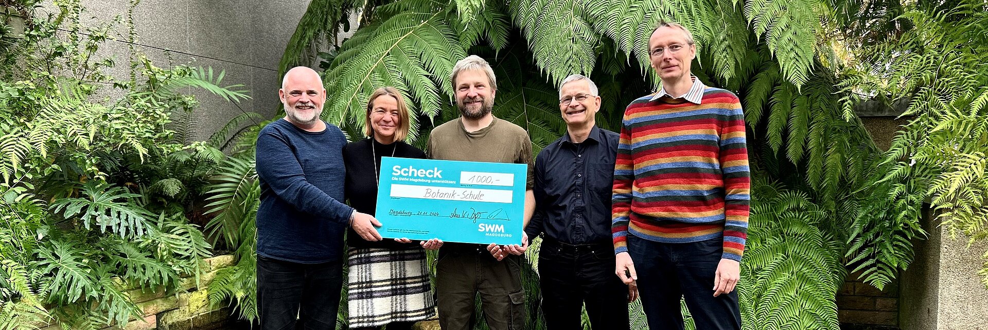 Mitarbeiter der SWM Magdeburg übergeben in den Gruson Gewächshäusern einen Spendenscheck an Mitarbeiter der Botanikschule.