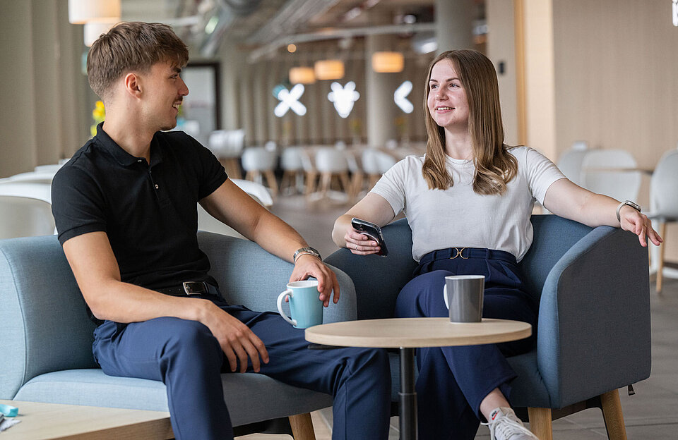 kaufmännische Auszubildende und Dualer Student sitzen in Kantine trinken in der Pause einen Kaffee zusammen